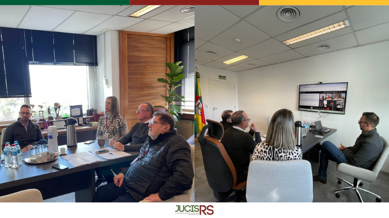 Sala de reuni&otilde;es com 4 pessoas sentadas em tono de uma mesa retangular e marrom. 