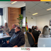 Sala de reuni&otilde;es com 4 pessoas sentadas em tono de uma mesa retangular e marrom. 